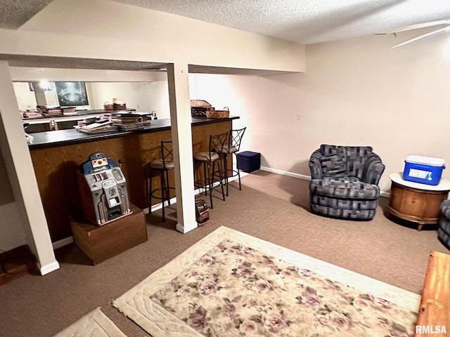 interior space with a textured ceiling, carpet floors, a bar, and baseboards