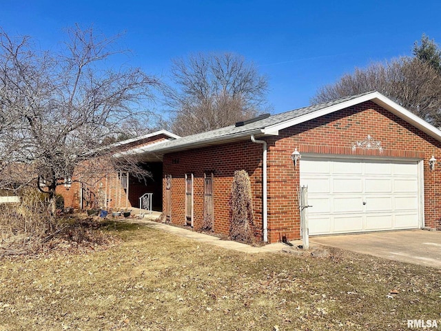 view of side of property featuring an attached garage, a yard, driveway, and brick siding