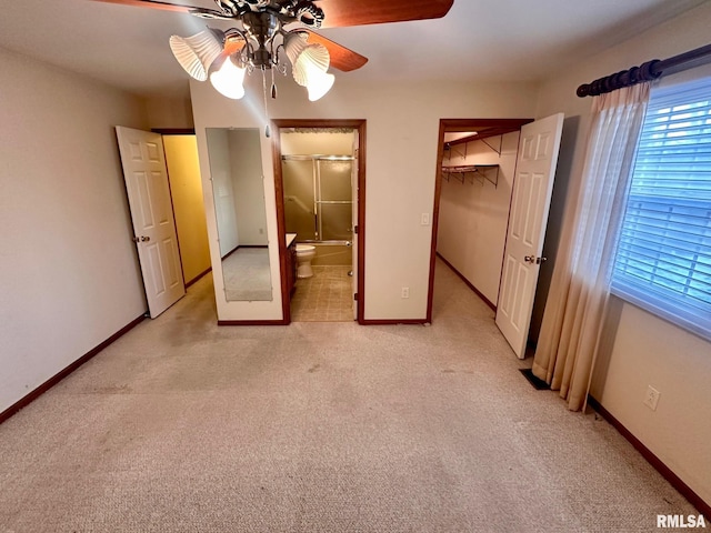 unfurnished bedroom featuring a closet, light colored carpet, ensuite bath, and baseboards