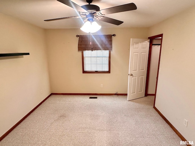 carpeted empty room with visible vents, ceiling fan, and baseboards