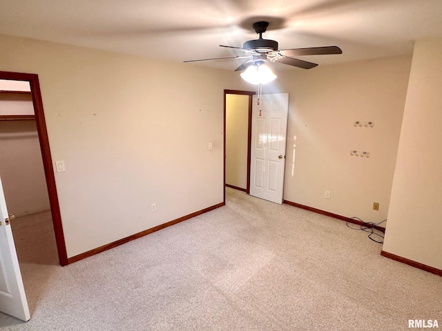 spare room with ceiling fan, baseboards, and light colored carpet