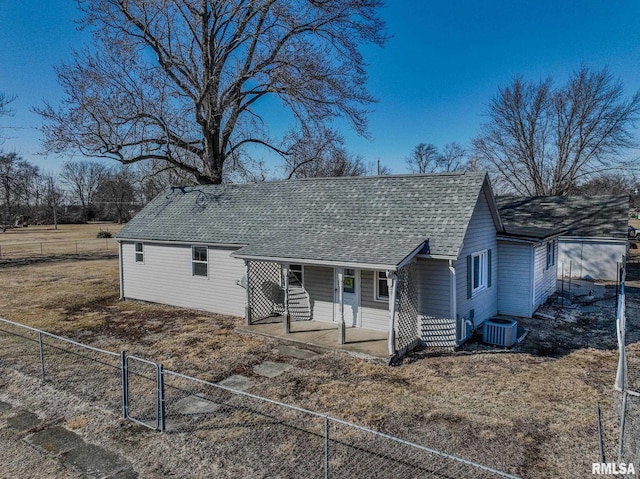 view of front of home with a patio, roof with shingles, fence, and central air condition unit