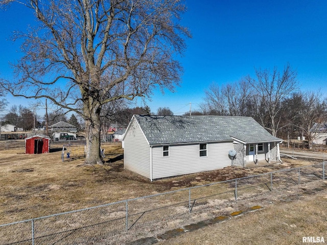 view of property exterior with a yard, roof with shingles, and fence