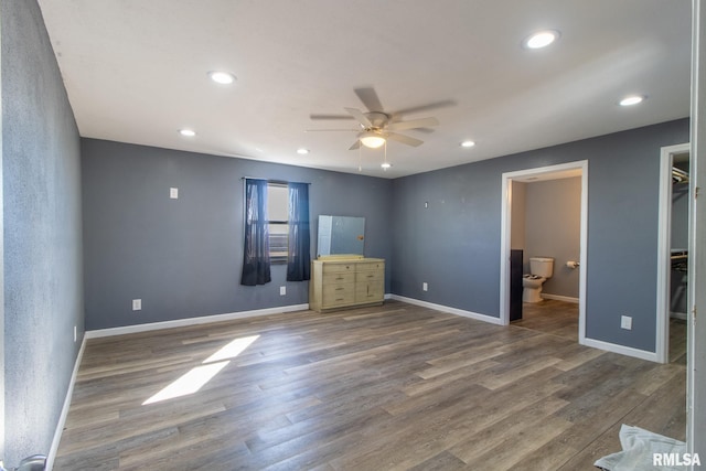 unfurnished bedroom with a spacious closet, baseboards, dark wood-type flooring, and recessed lighting