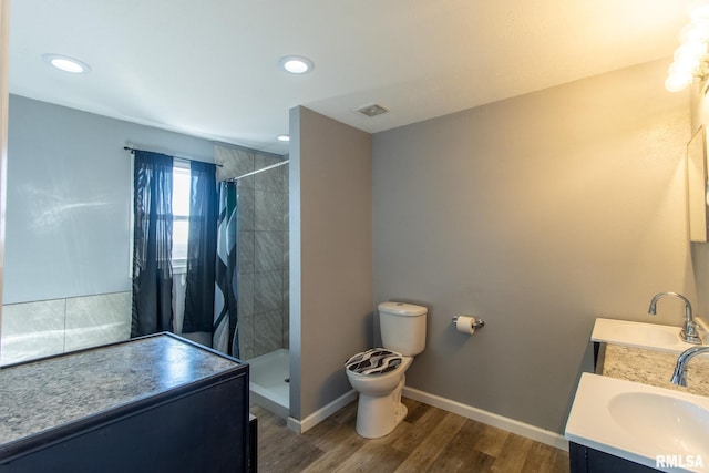 bathroom with toilet, vanity, a shower stall, wood finished floors, and baseboards