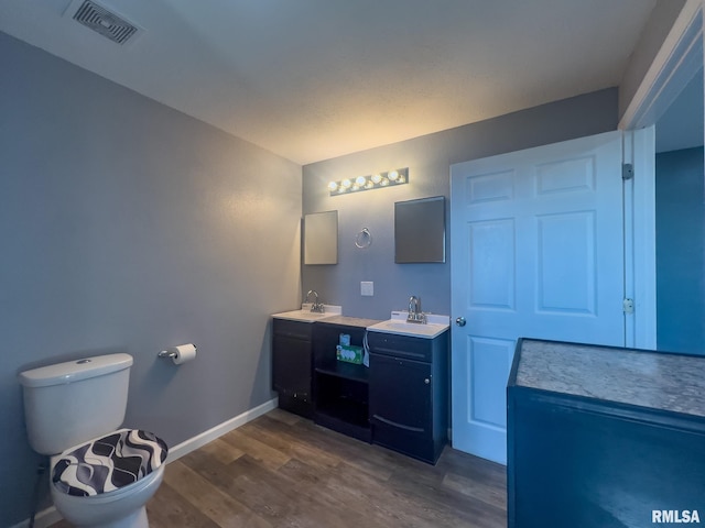 bathroom with wood finished floors, a sink, visible vents, and baseboards