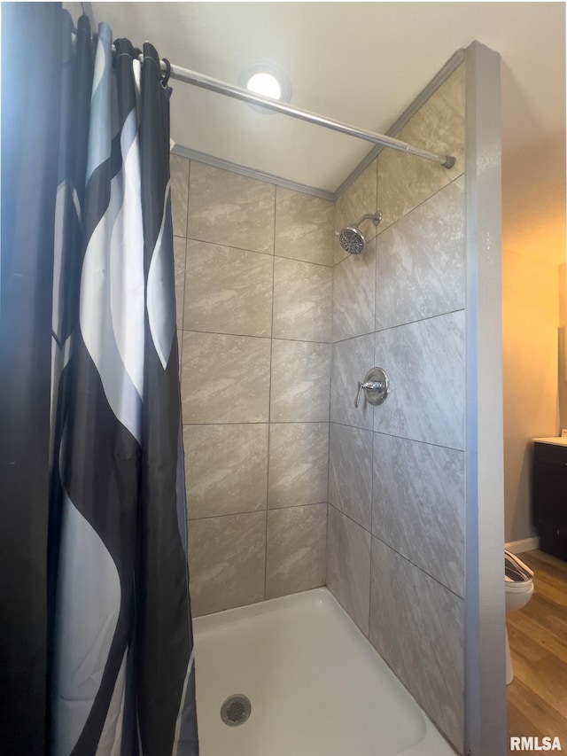 full bath featuring wood finished floors, a shower stall, and toilet