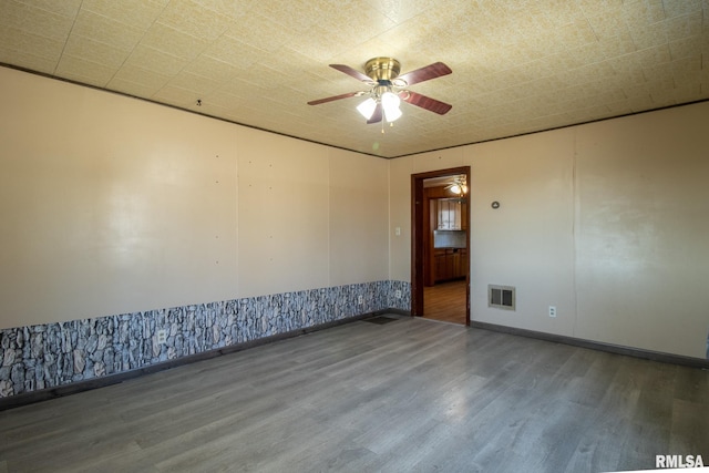 spare room with a ceiling fan, visible vents, and wood finished floors