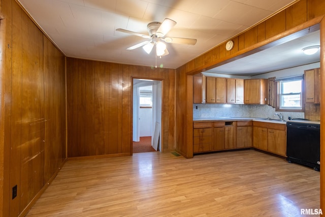 kitchen with black dishwasher, light countertops, brown cabinetry, and light wood-style floors