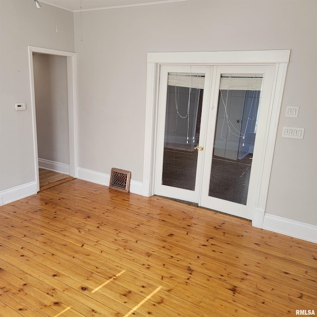 spare room featuring french doors, hardwood / wood-style flooring, visible vents, and baseboards