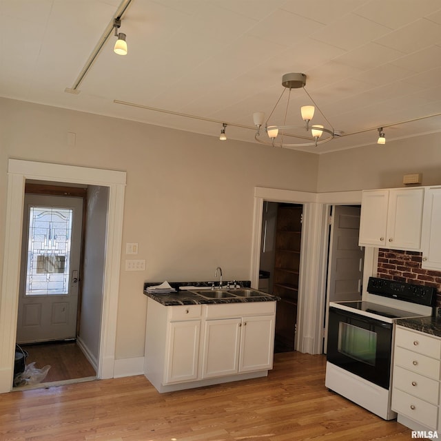 kitchen with electric stove, dark countertops, decorative light fixtures, white cabinetry, and a sink