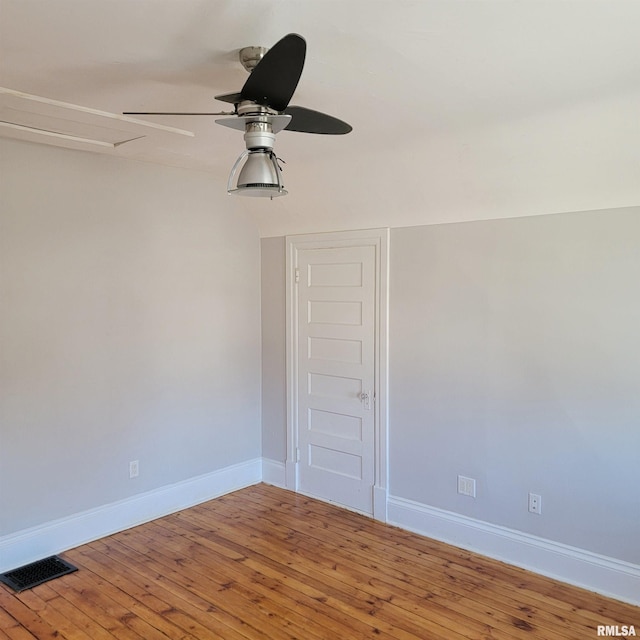 spare room featuring baseboards, wood-type flooring, visible vents, and a ceiling fan