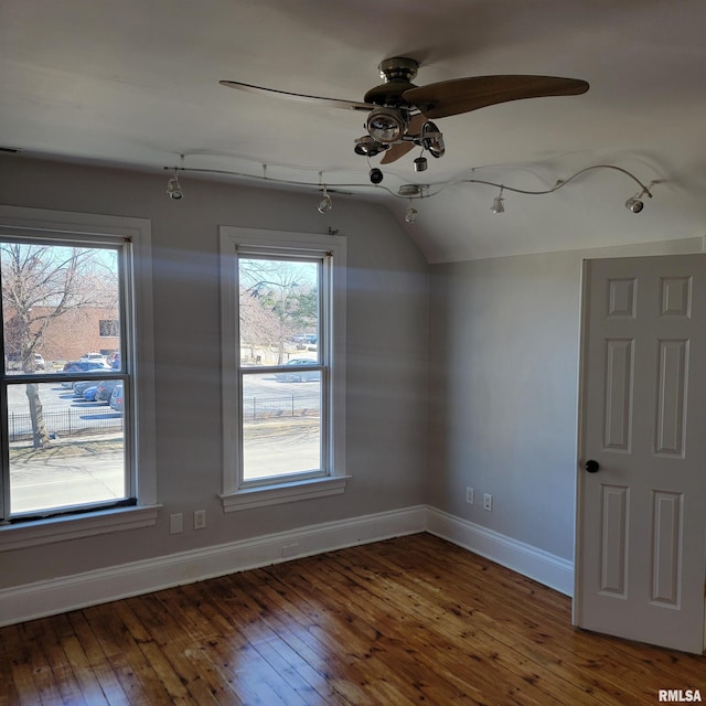 interior space featuring dark wood-style floors, lofted ceiling, a ceiling fan, and baseboards