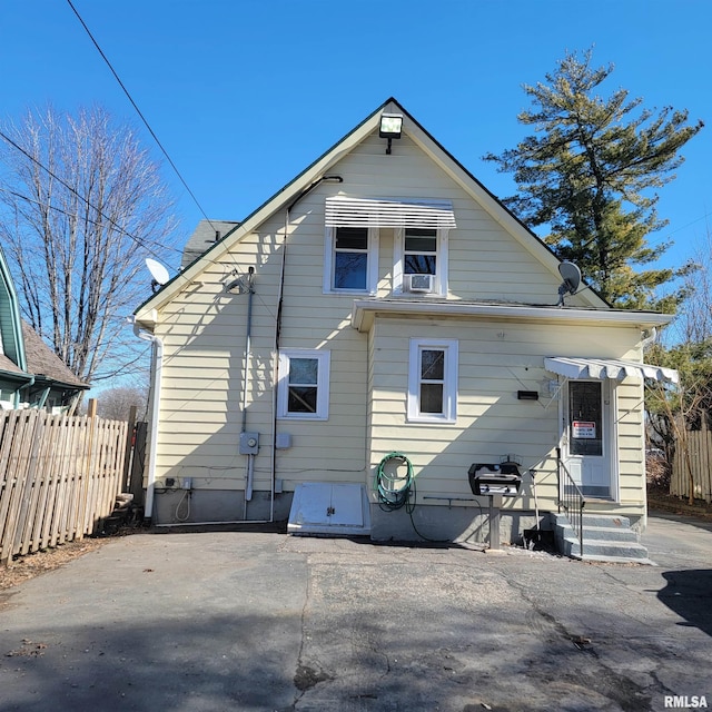 rear view of property with entry steps, a patio area, and fence