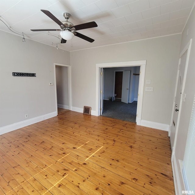 unfurnished room featuring ceiling fan, hardwood / wood-style floors, visible vents, and baseboards