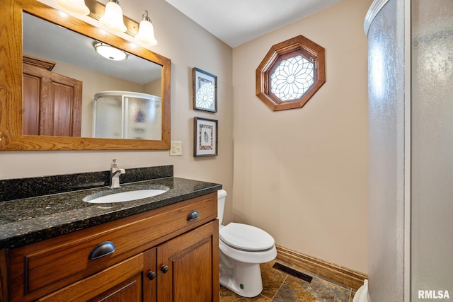 full bathroom featuring toilet, vanity, visible vents, baseboards, and a shower stall