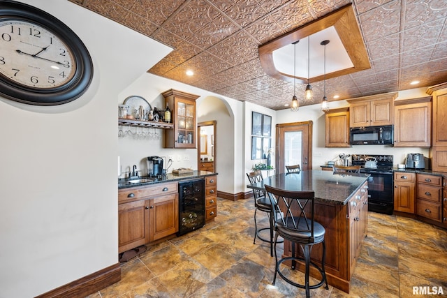 kitchen with beverage cooler, baseboards, an ornate ceiling, a kitchen breakfast bar, and black appliances