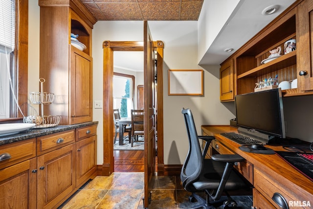 home office with stone finish floor, a sink, and baseboards