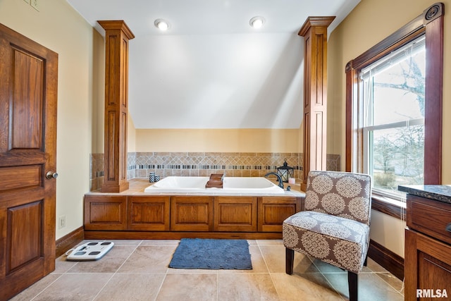 full bathroom with vaulted ceiling, tile patterned floors, a garden tub, and ornate columns