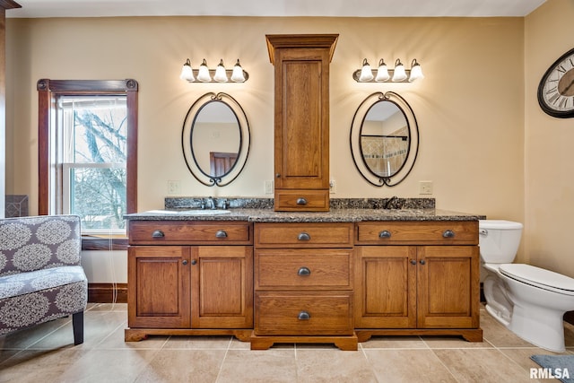 full bath with toilet, tile patterned flooring, double vanity, and a sink