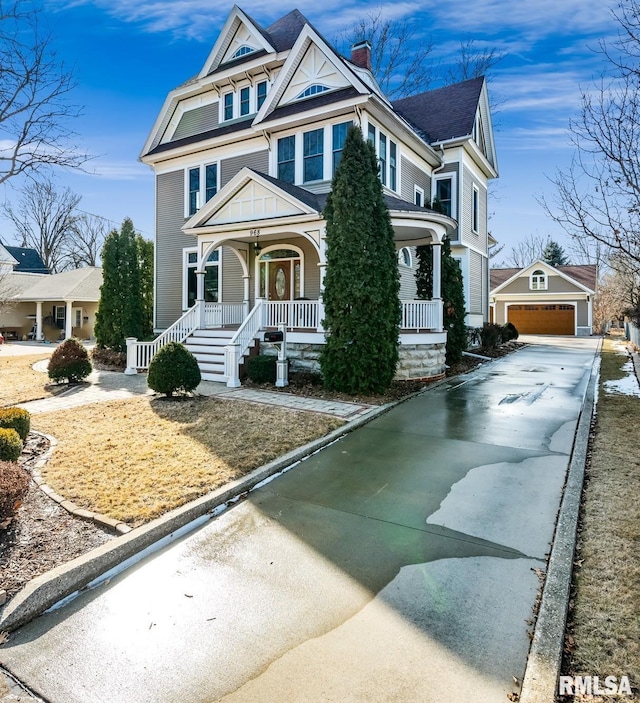 view of front of property with a garage, covered porch, a chimney, and an outdoor structure