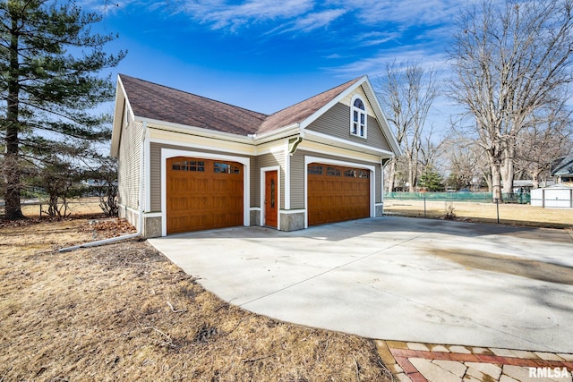 view of home's exterior featuring roof with shingles, fence, and driveway