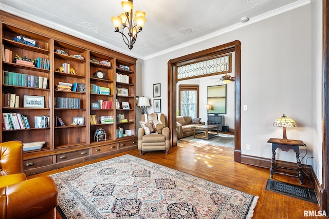 sitting room featuring baseboards, ceiling fan with notable chandelier, wood finished floors, and crown molding