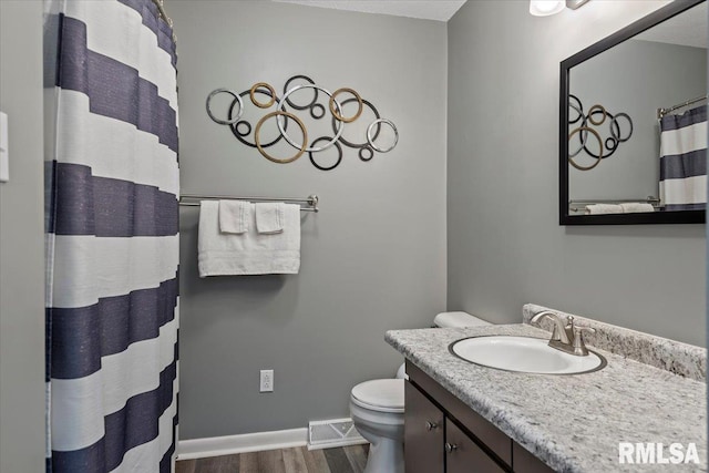 bathroom featuring vanity, wood finished floors, visible vents, baseboards, and toilet