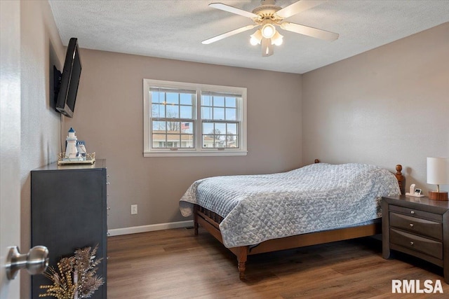 bedroom with baseboards, a textured ceiling, and wood finished floors