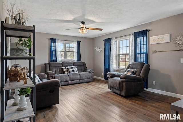 living room with baseboards, a textured ceiling, ceiling fan, and wood finished floors