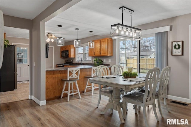 dining room featuring visible vents, light wood-type flooring, and baseboards