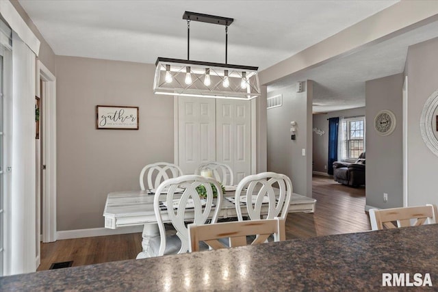 dining space featuring wood finished floors, visible vents, and baseboards