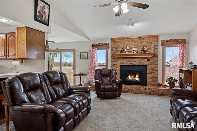 living room featuring a ceiling fan, carpet, a brick fireplace, and vaulted ceiling