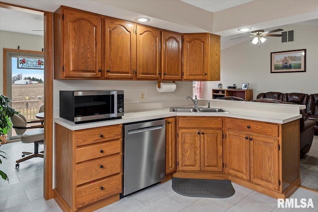 kitchen with stainless steel appliances, visible vents, brown cabinetry, a sink, and a peninsula