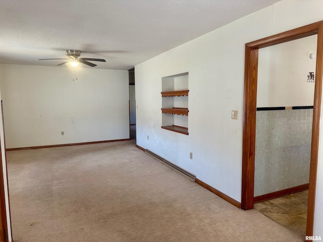 carpeted empty room with built in features, a baseboard heating unit, a ceiling fan, a textured ceiling, and baseboards