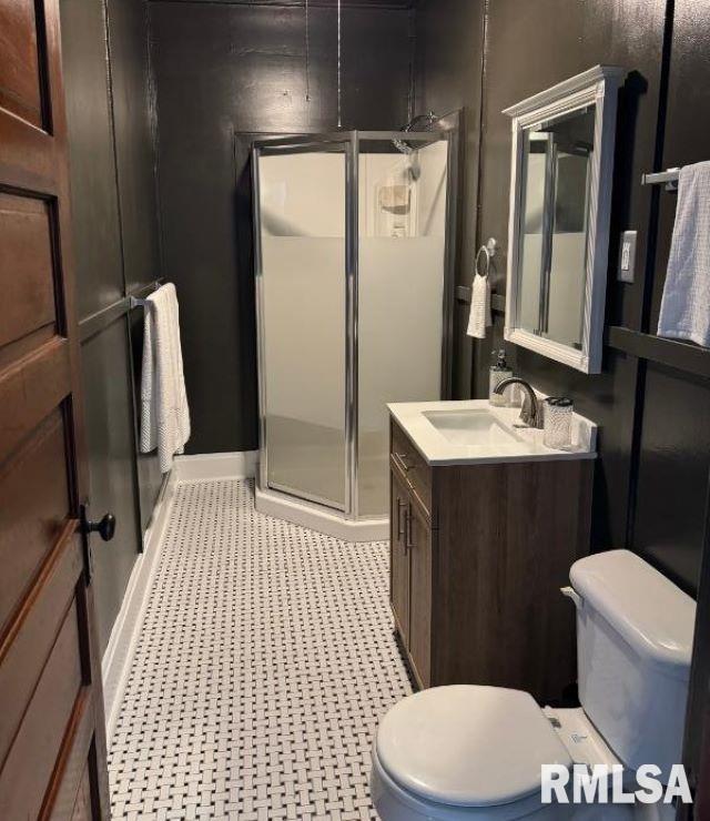 bathroom featuring vanity, a shower stall, toilet, and baseboards