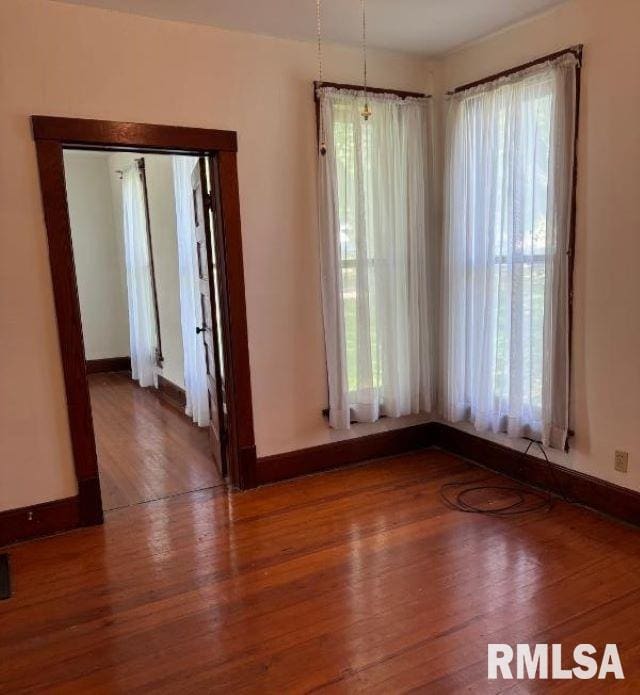 empty room with baseboards and wood finished floors