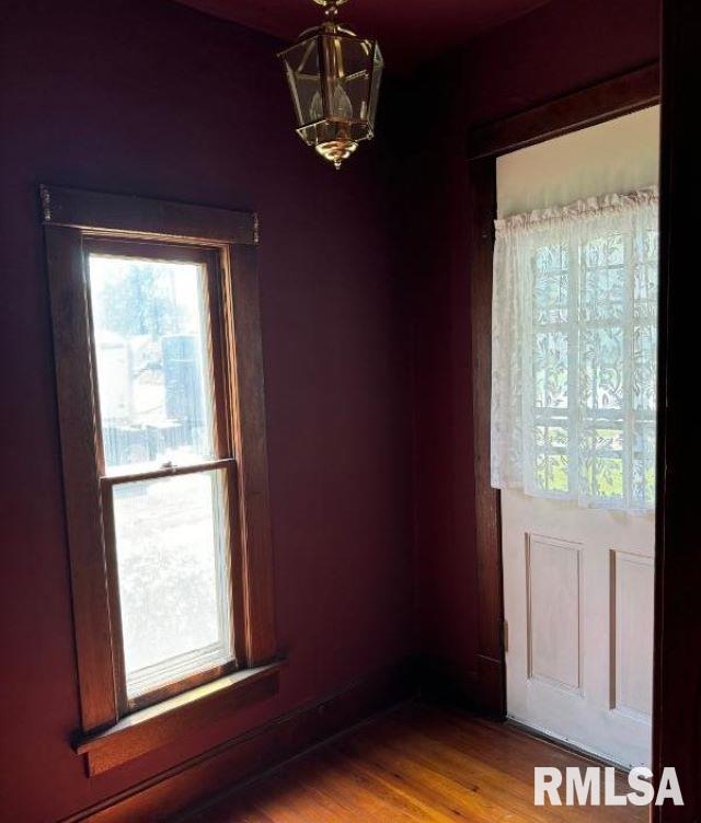 spare room featuring wood finished floors and a notable chandelier