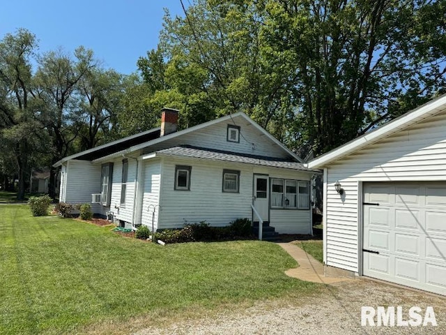 view of side of property with entry steps, a lawn, a chimney, and a garage