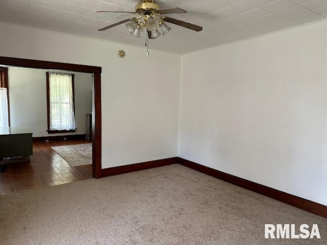 carpeted spare room with ceiling fan and baseboards