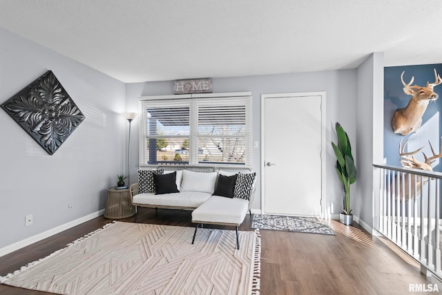 sitting room with baseboards, a textured ceiling, and wood finished floors