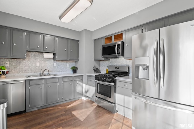 kitchen with tasteful backsplash, gray cabinets, appliances with stainless steel finishes, and a sink