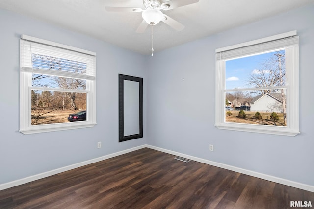 empty room featuring visible vents, ceiling fan, dark wood-type flooring, and baseboards