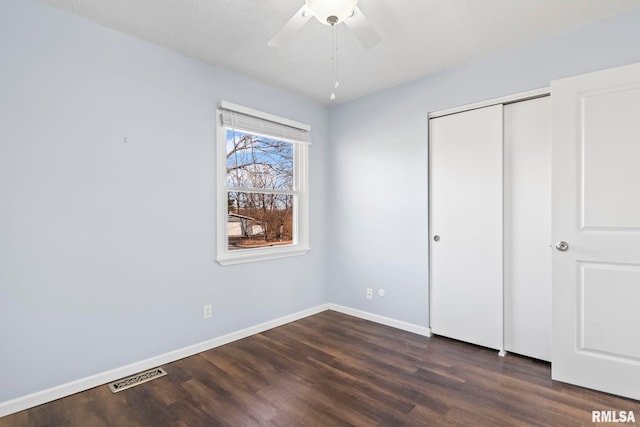 unfurnished bedroom featuring visible vents, baseboards, a closet, and dark wood-style floors