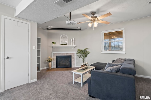 carpeted living area with visible vents, a textured ceiling, ceiling fan, and a fireplace