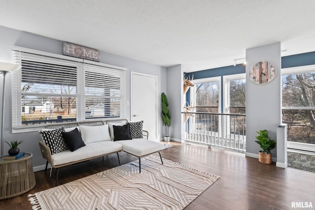 living room featuring a textured ceiling, baseboards, and wood finished floors