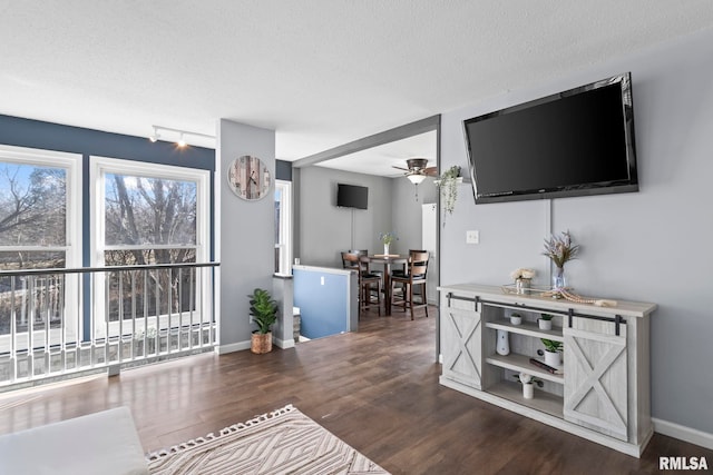 living room featuring track lighting, baseboards, wood finished floors, a textured ceiling, and a ceiling fan