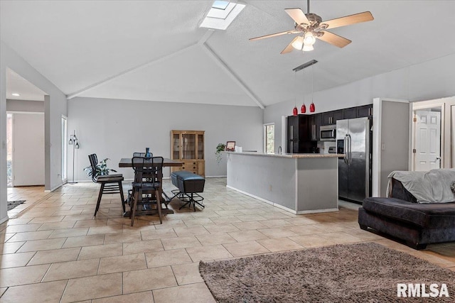 dining area featuring a skylight, light tile patterned floors, visible vents, ceiling fan, and high vaulted ceiling