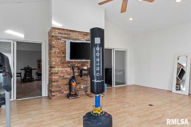 exercise room featuring high vaulted ceiling, ceiling fan, and wood finished floors