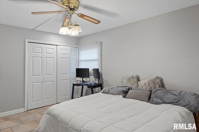 bedroom with light tile patterned floors, a closet, a ceiling fan, and baseboards